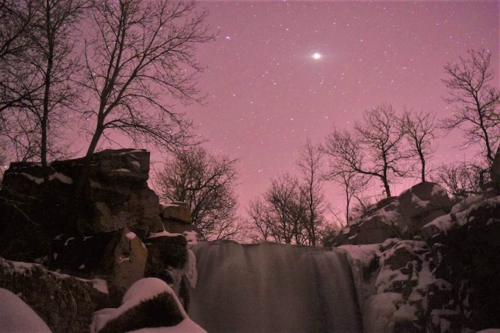 "Winnewissa Under Stars" (Winnewissa surrounded by a dusting of snow on the cliffs and a blanket of stars overhead). Credit: Pipestone National Monument (National Park Service), public domain.
