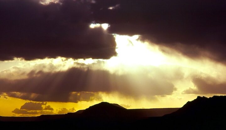 Rugged landscape bathed in the golden unseen sunset. Dark, rolling hills stretch towards a horizon ablaze with yellow.